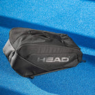 Vooraanzicht zwarte HEAD Pro X Padel Bag L Black: ruime, padeltas van gerecycled materiaal op een blauw padel terrein