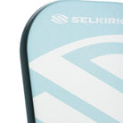 Close-up van het slagoppervlak van de lichtblauwe Selkirk AMPED Pro Air Epic pickleball racket met groot wit Selkirk-logo op het blad.