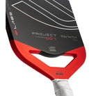 Close-up van de Selkirk LABS 007 Invikta pickleball paddle, zwart blad met rode onderzijde, wit handvat en het Selkirk-logo in zwart met witte omlijning op het slagooppervlak.