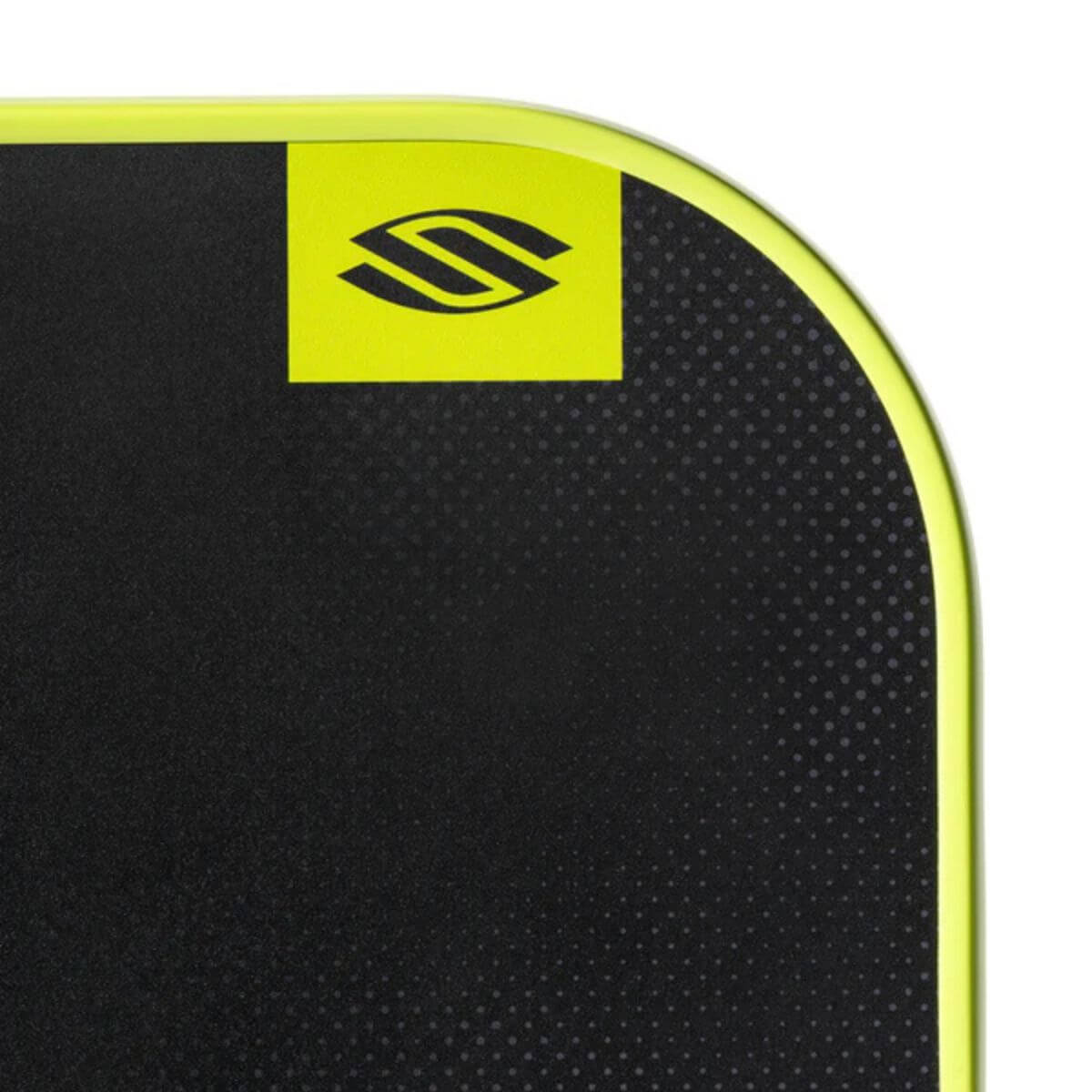 Close-up van de bovenzijde van een zwarte pickleball racket met gele rand handvat. 